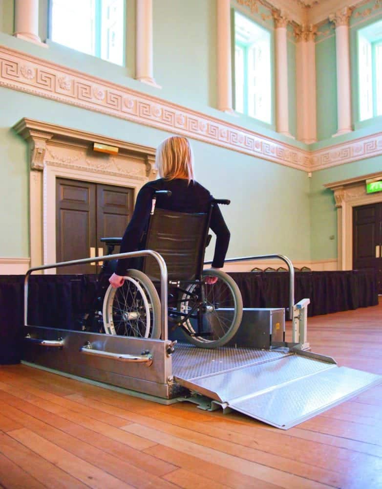 woman using portable wheelchair lift at event venue